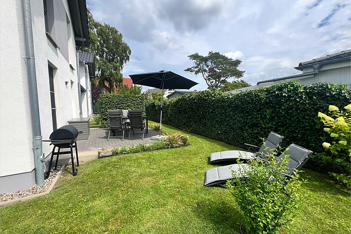 Garden with sun loungers, hedge and terrace in summer