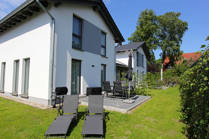 The holiday home with terrace, sun loungers and garden on a summer’s day