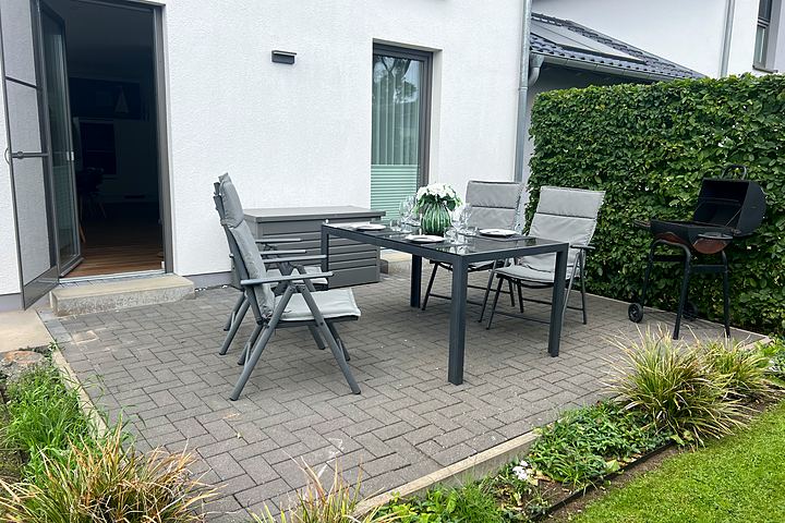 Terrace with dining table, folding chairs and barbecue