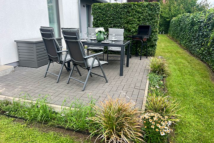 South-facing terrace with garden furniture, barbecue and flower bed