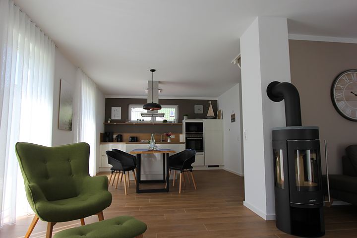 Living room with wood-burning stove, wing chair and view of the kitchen